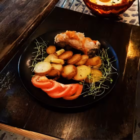 a plate of duck, potatoes, tomatoes and cress in a lviv galician restaurant