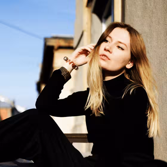 pensive girl dressed in black sat on a balcony in lviv