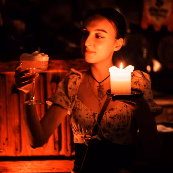 a ukrainian girl carrying a glass of beer by candlelight